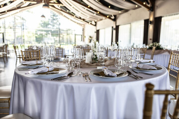 Wedding setting and decorated tables in a beautiful modern interior of a performance hall with a modern light ceiling of wooden construction