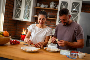 Young couple shares tender moment in morning kitchen, preparing fresh ingredients for their breakfast together.