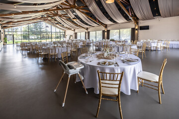 Wedding setting and decorated tables in a beautiful modern interior of a performance hall with a modern light ceiling of wooden construction