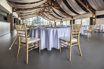 Wedding setting and decorated tables in a beautiful modern interior of a performance hall with a modern light ceiling of wooden construction