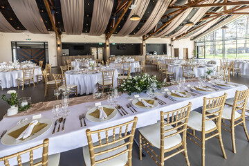 Wedding setting and decorated tables in a beautiful modern interior of a performance hall with a modern light ceiling of wooden construction
