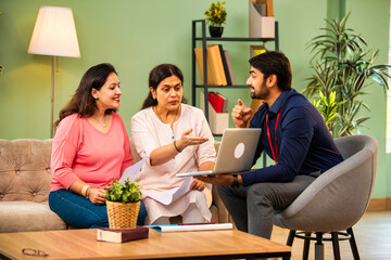 Indian mother and daughter consult male advisor for insurance or loan in cozy home interior