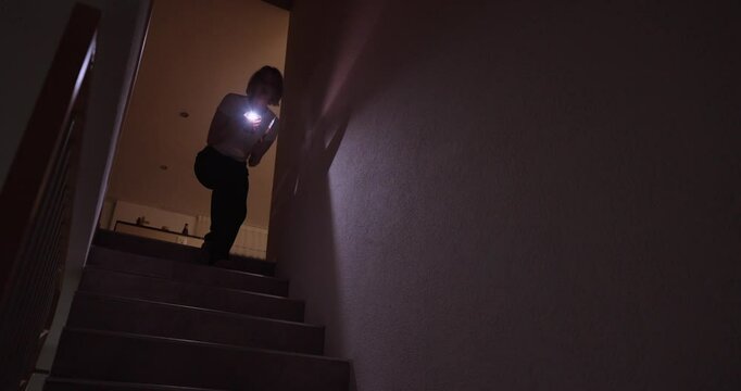 woman fearfully goes into the basement with a knife in her hand and a flashlight 50P
