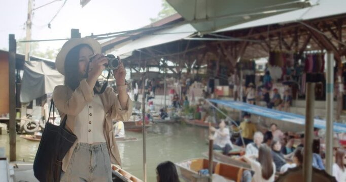 Asian tourist woman taking picture and smile and travel along the canel Damnoen Saduak Floating Market ratchaburi,Thailand