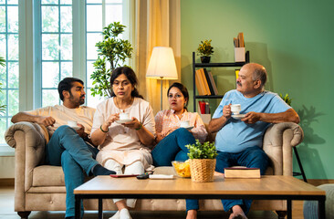 Discussing topic over tea, Indian family sitting together on couch having an important talk