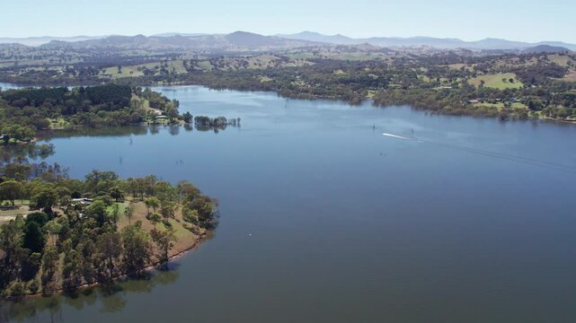 Aerial footage of Lake Eildon in the sun with a speed boart in the distance, near Mansfield in central Victoria, Australia. The storage was 97% full. February 2024.