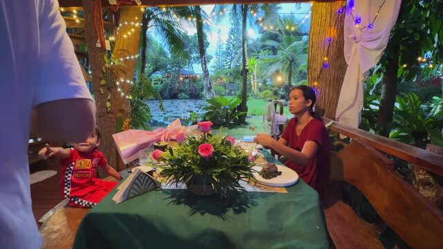 Family enjoys festive dinner in resort gazebo near pond