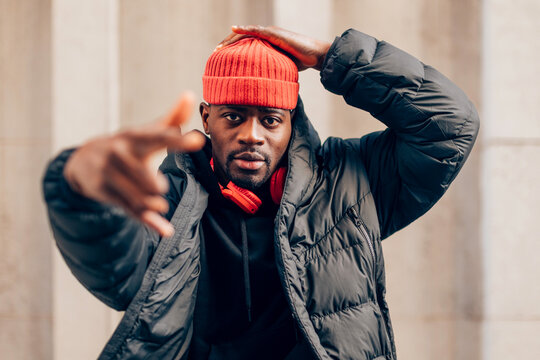 Stylish man wearing red beanie and headphones making hand gesture