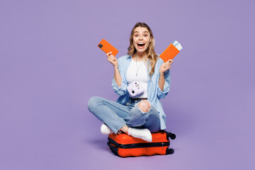 Traveler woman wear blue clothes sit on bag use mobile cell phone hold ticket isolated on plain...