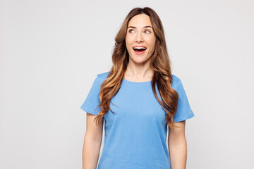 Fototapeta premium Young shocked surprised Caucasian woman she wears blue t-shirt casual clothes look aside on empty blank area mock up isolated on plain solid white color background studio portrait. Lifestyle concept.