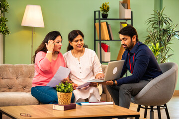 Indian mother and daughter consult male advisor for insurance or loan in cozy home interior