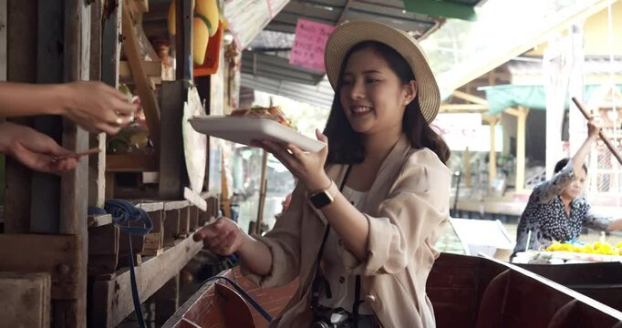 Asian tourist woman taking picture and smile and travel along the canel Damnoen Saduak Floating Market ratchaburi,Thailand