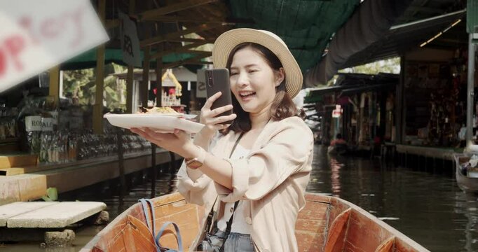 Asian tourist woman taking picture and smile and travel along the canel Damnoen Saduak Floating Market ratchaburi,Thailand