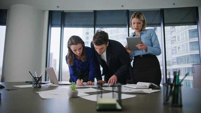 Business team analyzing documents at office desk. Colleagues reviewing papers