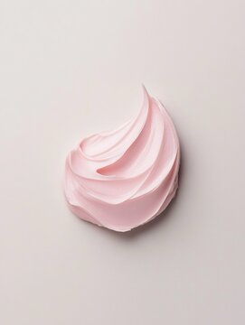 Una noce di crema per la cura della pelle rosa densa e cremosa su uno sfondo grigio chiaro tenue.