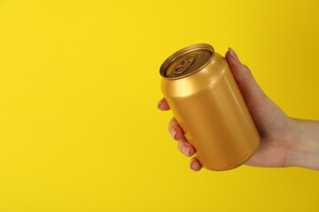Woman with tin can on yellow background, closeup. Space for text