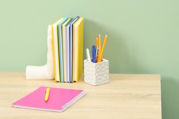 Stylish workplace with stationery on wooden desk near light green wall