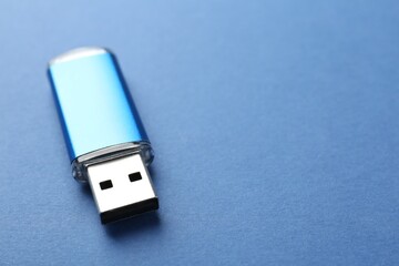 One flash drive on blue background, closeup. Space for text