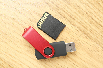 Flash drive and SD memory card on wooden background, flat lay