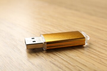 One flash drive on wooden background, closeup
