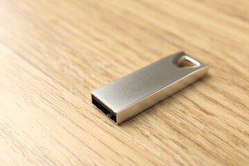 One flash drive on wooden background, closeup. Space for text