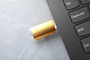 Flash drive connected to laptop on gray textured table, top view