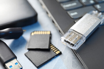 Flash drive, SD memory cards, external hard disk and laptop on gray table, closeup