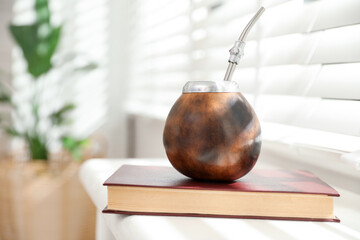 Traditional yerba mate tea and book on windowsill indoors