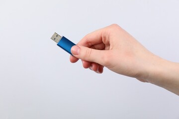 Man with modern flash drive on light grey background, closeup