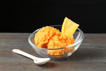 Balls of tasty orange sorbet, fresh fruit, mint and spoon on wooden table, closeup