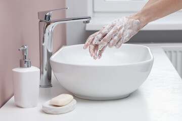 Woman washing hands at sink in bathroom, closeup