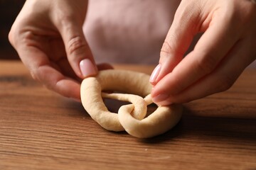 Woman shaping pretzels at wooden table, closeup