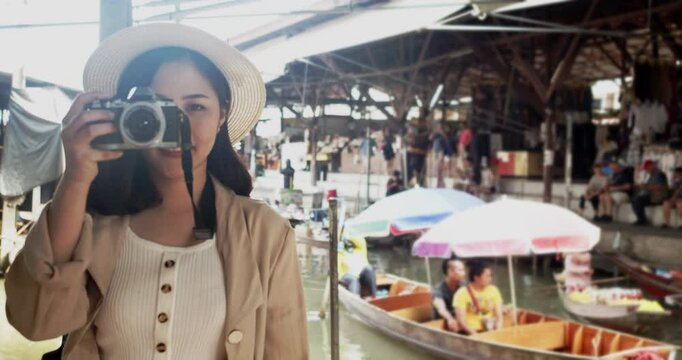 Asian tourist woman taking picture and smile and travel along the canel Damnoen Saduak Floating Market ratchaburi,Thailand