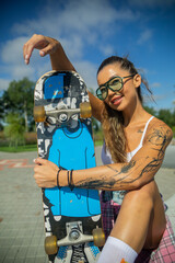 Mulatto girl walks along the embankment with a skateboard and a volleyball, a mulatto girl plays...