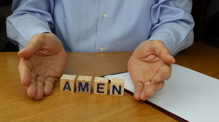 Testo AMEN scritto su un blocco di legno con le mani dell'uomo nelle vicinanze