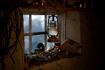 Garage in the village. Rural entourage. Bat lamp. Welder's inventory. Glimpses of light illuminate the garage tools. Vintage, kerosene lamp. Cobwebs encircle the window.