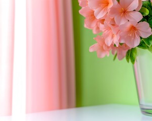 Peach-colored artificial flowers in a clear vase sit on a white surface against a pale green wall and pink curtain