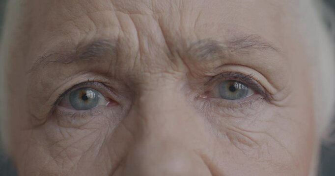 Close-up slow motion portrait of unhappy senior woman's eyes looking at camera while retired lady feeling worried and miserable.