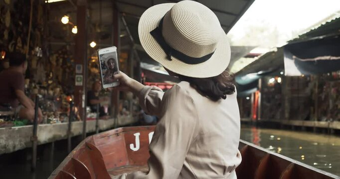 Asian tourist woman taking picture and smile and travel along the canel Damnoen Saduak Floating Market ratchaburi,Thailand