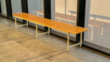 Sleek natural wood bench in sunlit modern indoor space with concrete flooring and glass walls for contemporary urban design inspiration