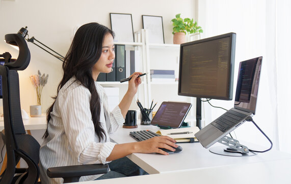 Software developer working on coding project with multiple monitors in modern home office..