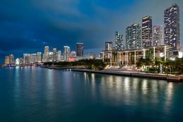 Fototapeta premium Panoramic view of modern skyscrapers glowing at dusk alongside the waterfront Maurice A. Ferré Park in downtown Miami.
