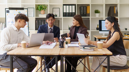 Group of businesspeople brainstorming ideas and reviewing data in a modern office.
