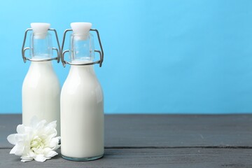 Fresh milk and flower on wooden table against light blue background. Space for text