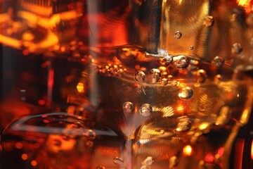 Refreshing cola with ice cubes as background, macro view