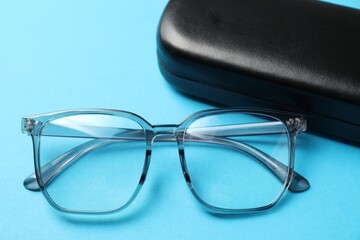 Case with stylish glasses on light blue background, closeup