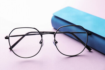 Case with stylish glasses on violet background, closeup