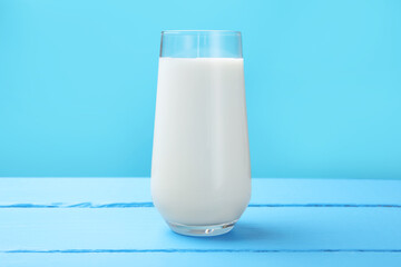 Fresh milk in glass on light blue wooden table