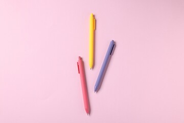 Set of ballpoint pens on pink background, flat lay