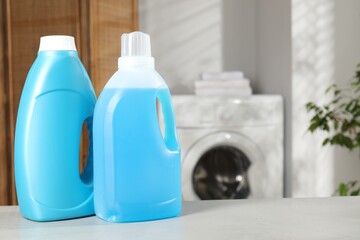 Bottles of fabric softener on light grey table indoors, space for text